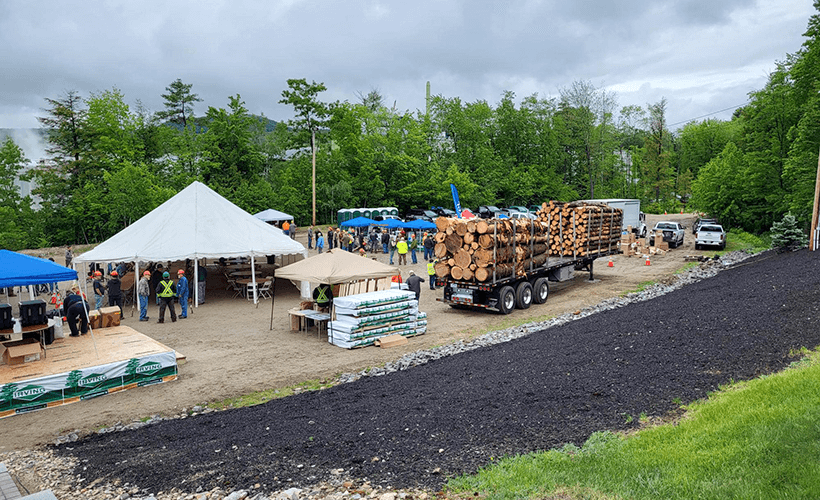 Wide view of the event, including tents and log trucks