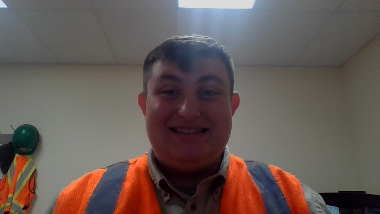Owen Lewis in an office, wearing a high-visibility vest